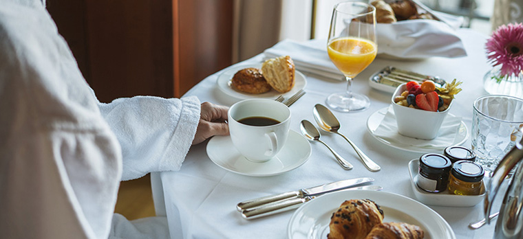 a waiter placing a cup of coffee on a nicely-laid table